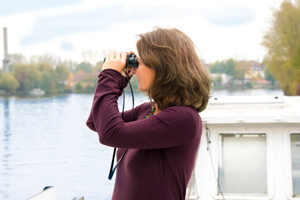 Kerstin Hack schaut durchs Fernglas auf die Spree